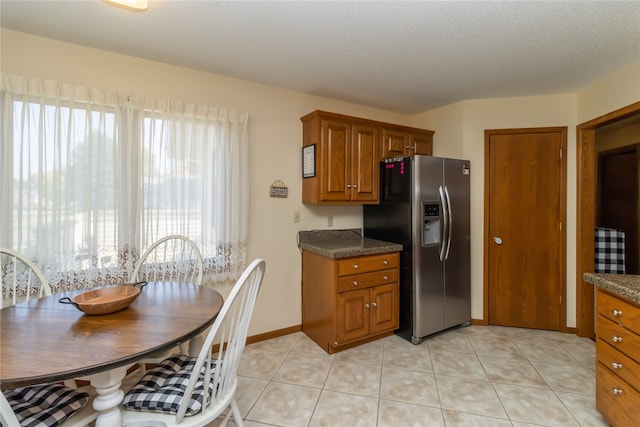 kitchen with stainless steel refrigerator with ice dispenser, light tile patterned floors, and a textured ceiling