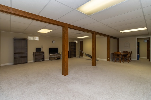 basement featuring a paneled ceiling and light colored carpet