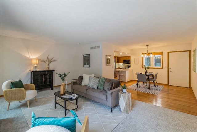 living room featuring light carpet and a notable chandelier