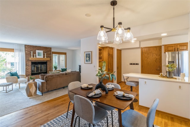 dining area featuring light hardwood / wood-style flooring and a brick fireplace