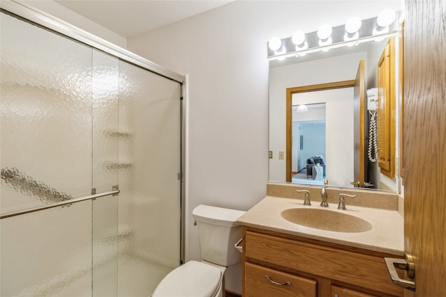 bathroom with vanity, toilet, and a shower with door