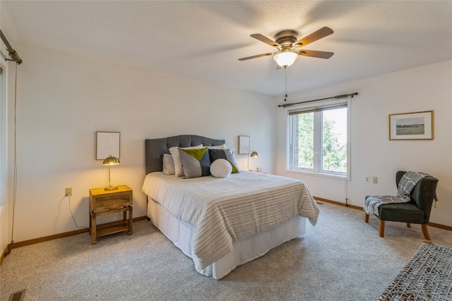 bedroom featuring a textured ceiling, ceiling fan, and light carpet