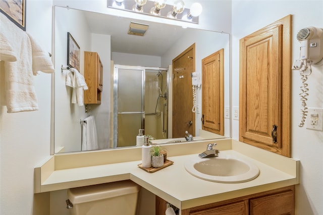 bathroom with a shower with door, vanity, and toilet