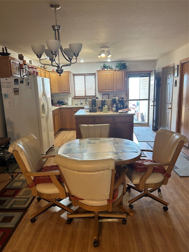 dining space featuring light hardwood / wood-style floors, a textured ceiling, and a chandelier