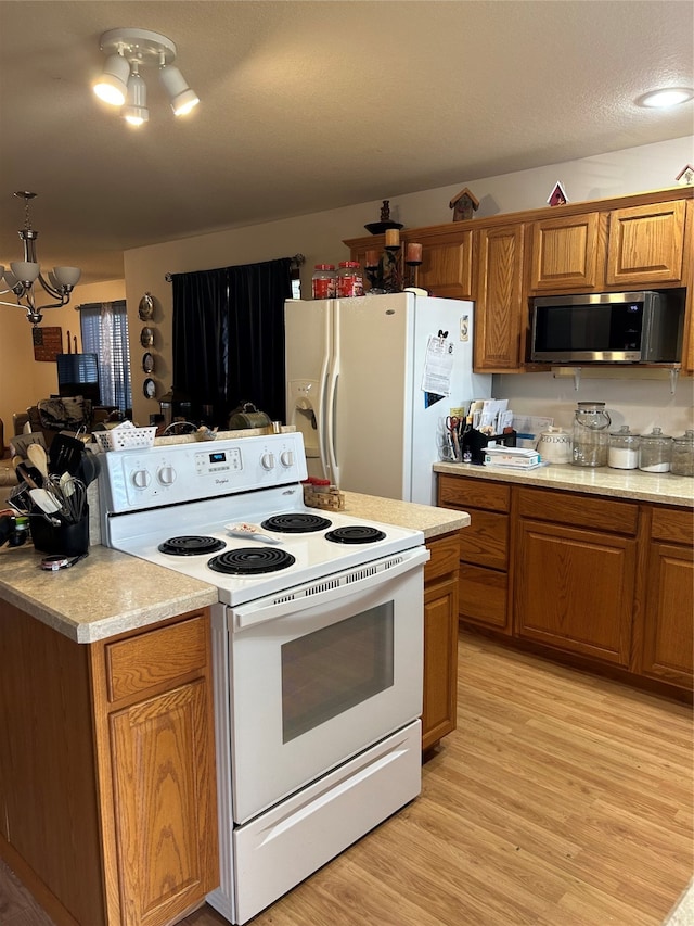 kitchen with white appliances, an inviting chandelier, and light wood-type flooring