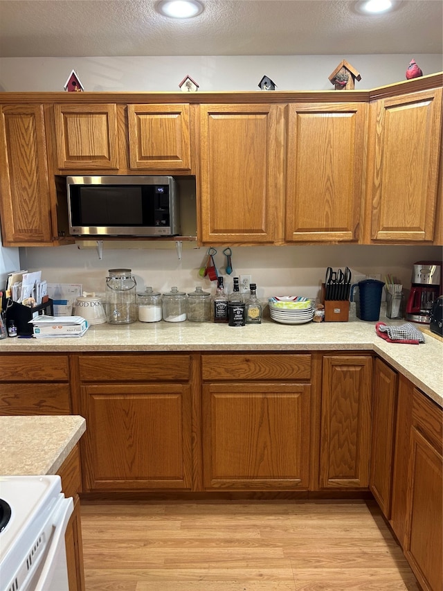 kitchen featuring light hardwood / wood-style flooring, a textured ceiling, and white range oven