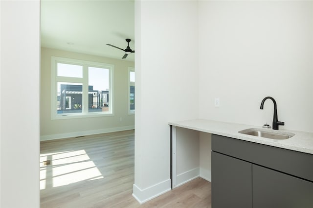 bar featuring ceiling fan, sink, and light hardwood / wood-style flooring