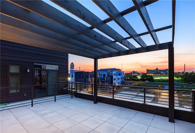 patio terrace at dusk featuring a balcony and a pergola