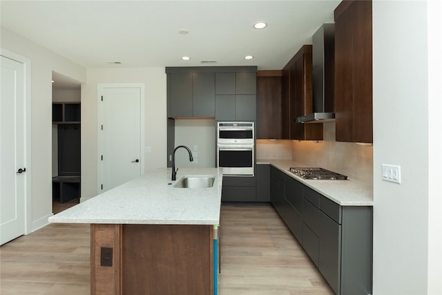 kitchen featuring light hardwood / wood-style floors, appliances with stainless steel finishes, a center island with sink, and sink