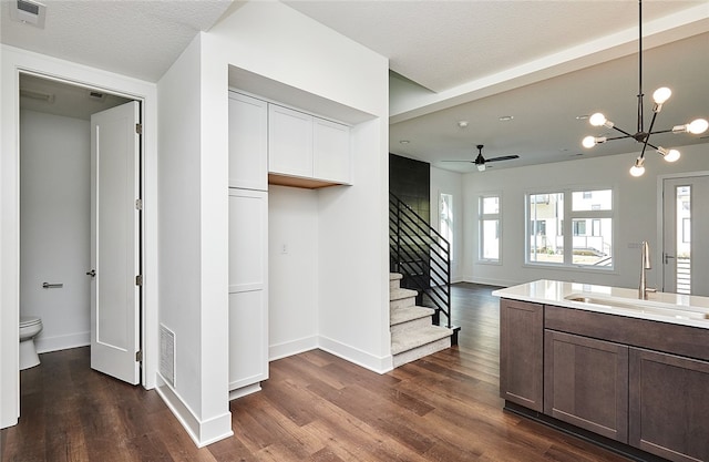 kitchen featuring pendant lighting, ceiling fan with notable chandelier, dark hardwood / wood-style flooring, sink, and a textured ceiling