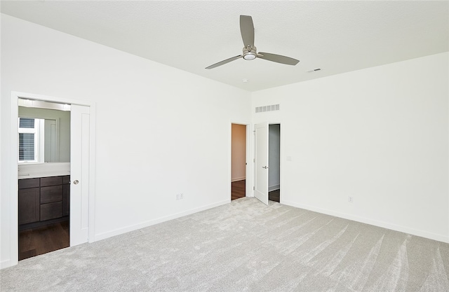 unfurnished bedroom with light carpet, ensuite bath, and ceiling fan