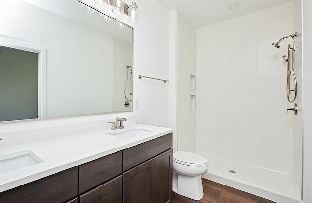 bathroom featuring vanity, toilet, hardwood / wood-style flooring, and tiled shower