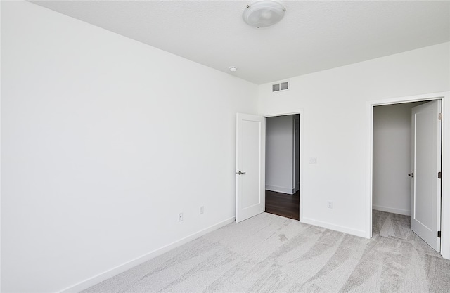 unfurnished bedroom with light colored carpet and a closet