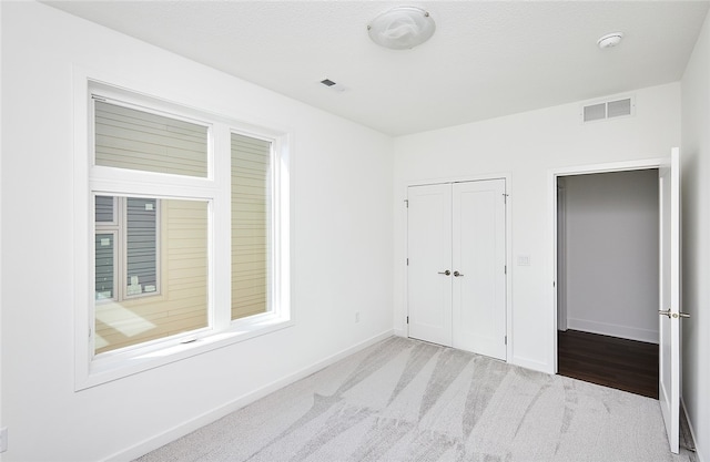 unfurnished bedroom with light carpet and a closet