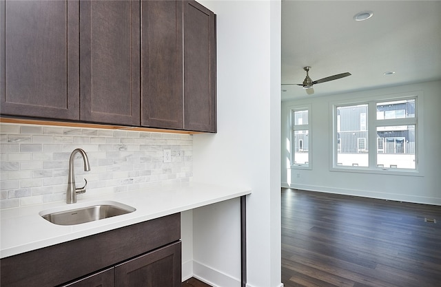 kitchen featuring dark wood-type flooring, backsplash, sink, and dark brown cabinets