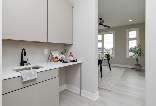 kitchen featuring sink, light hardwood / wood-style floors, tasteful backsplash, and ceiling fan