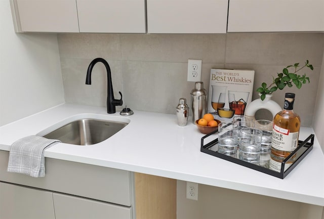 interior details with sink, white cabinets, and tasteful backsplash