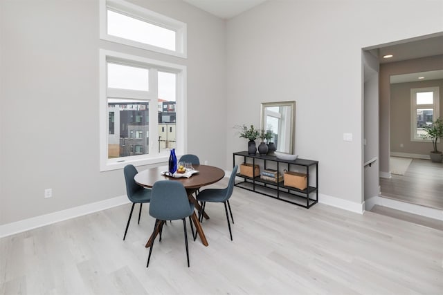 dining room with light hardwood / wood-style floors and a towering ceiling