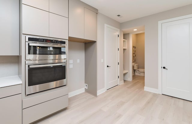 kitchen featuring stainless steel double oven and light hardwood / wood-style flooring