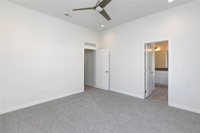 unfurnished bedroom featuring light carpet, connected bathroom, and ceiling fan