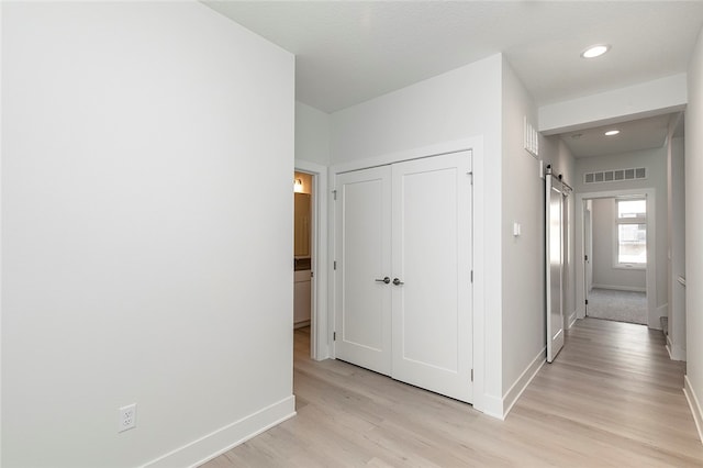 hall with a textured ceiling, light hardwood / wood-style floors, and a barn door