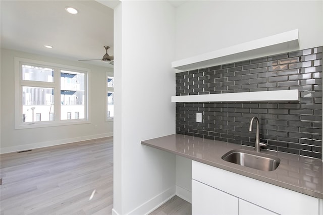 kitchen featuring light hardwood / wood-style floors, sink, white cabinetry, and decorative backsplash