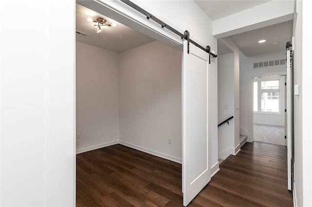 corridor with dark wood-type flooring and a barn door