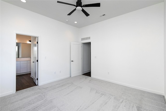 unfurnished bedroom with ceiling fan, light colored carpet, and ensuite bathroom