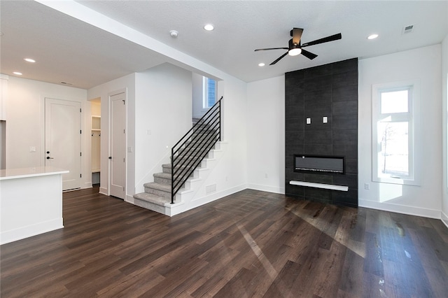 foyer with ceiling fan, a textured ceiling, a tiled fireplace, and dark hardwood / wood-style flooring