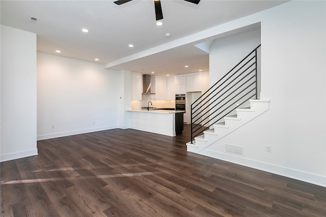 unfurnished living room featuring dark wood-type flooring, sink, a textured ceiling, and ceiling fan