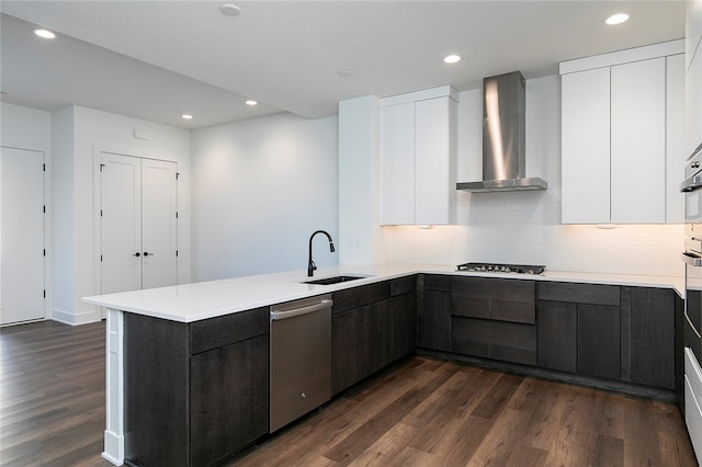 kitchen with appliances with stainless steel finishes, wall chimney range hood, and white cabinets