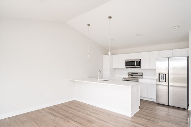 kitchen featuring vaulted ceiling, sink, hanging light fixtures, appliances with stainless steel finishes, and white cabinetry