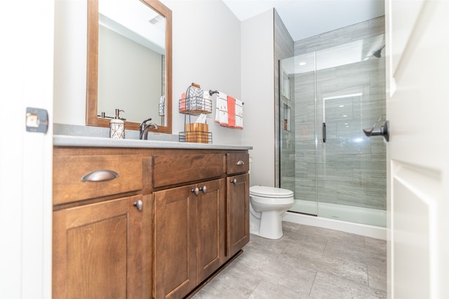 bathroom featuring a shower with door, vanity, and toilet