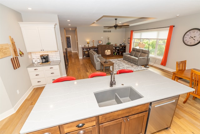 kitchen with ceiling fan, tasteful backsplash, sink, white cabinets, and stainless steel dishwasher