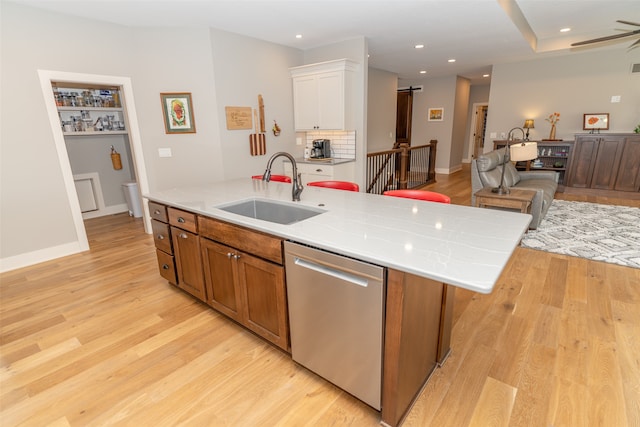 kitchen with light hardwood / wood-style flooring, sink, dishwasher, an island with sink, and white cabinetry