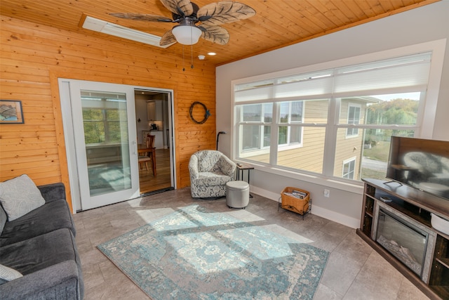 tiled living room featuring a skylight, wooden walls, plenty of natural light, and wood ceiling