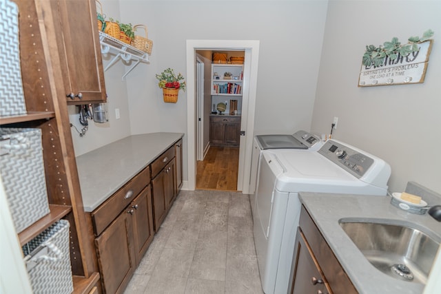 laundry room featuring independent washer and dryer, cabinets, light hardwood / wood-style flooring, and sink