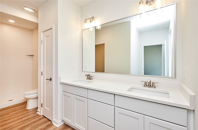 bathroom featuring wood-type flooring, vanity, walk in shower, and toilet