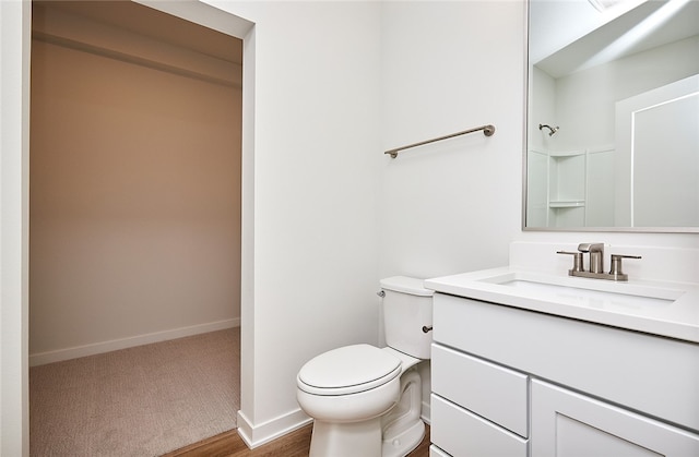 bathroom with toilet, vanity, and wood-type flooring