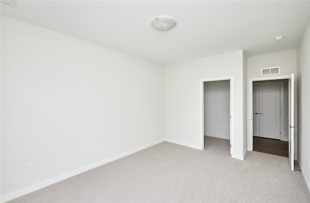 unfurnished bedroom with a closet and light colored carpet