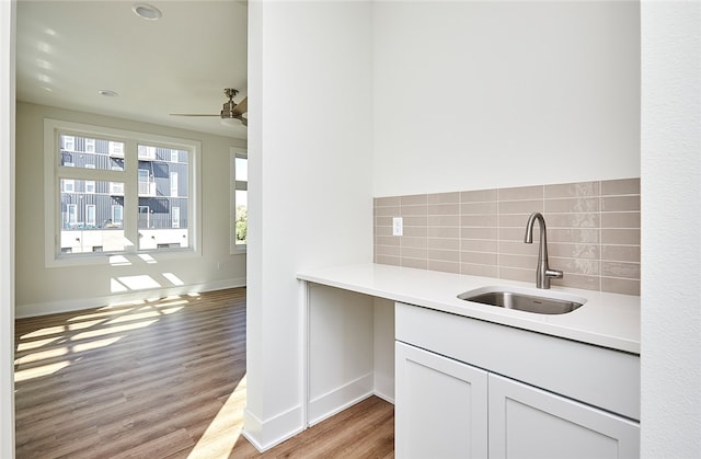 kitchen with ceiling fan, white cabinets, sink, tasteful backsplash, and light hardwood / wood-style flooring