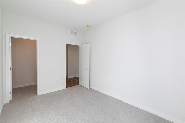 unfurnished bedroom with a walk in closet and light carpet