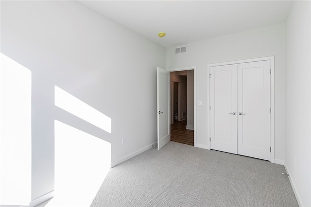 unfurnished bedroom featuring light carpet and a closet