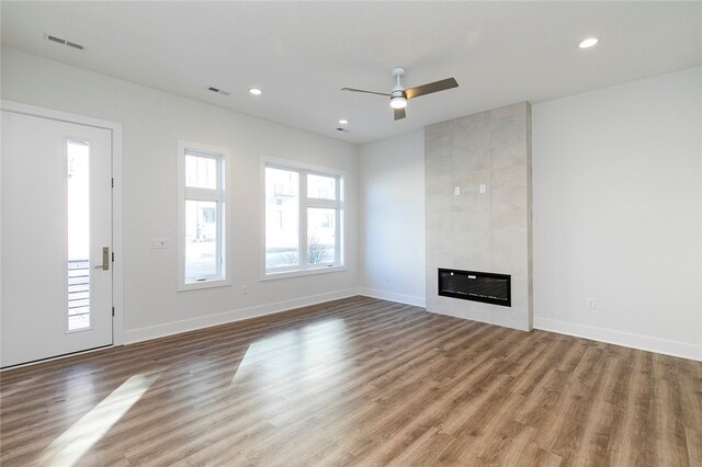 unfurnished living room featuring ceiling fan, light hardwood / wood-style flooring, and a tiled fireplace