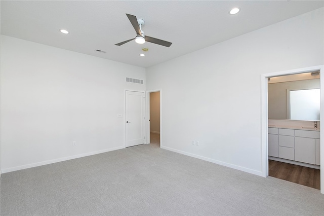 unfurnished bedroom with light carpet, connected bathroom, and ceiling fan