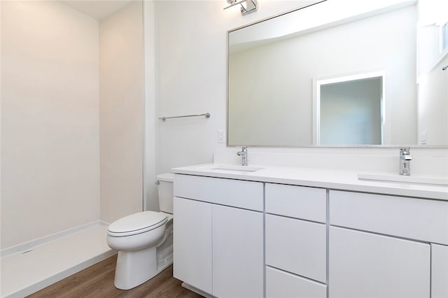 bathroom with hardwood / wood-style flooring, vanity, walk in shower, and toilet