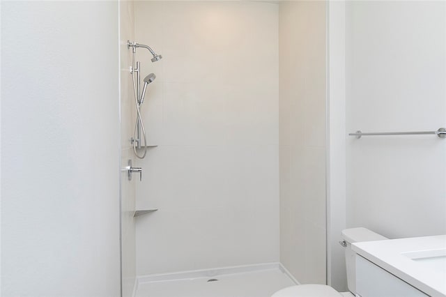 bathroom featuring a tile shower, vanity, and toilet