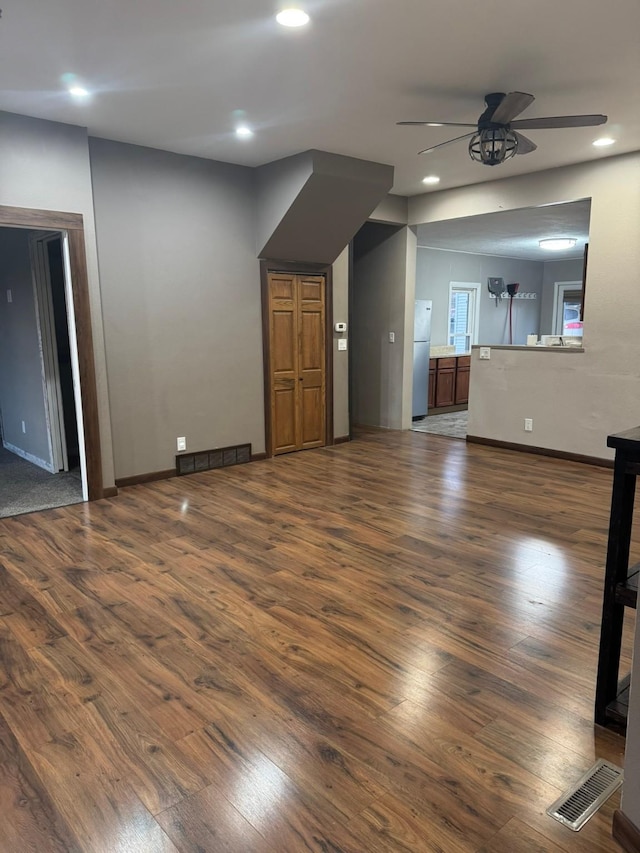 unfurnished living room featuring dark hardwood / wood-style flooring and ceiling fan