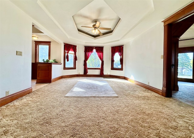 carpeted empty room featuring a tray ceiling, a wealth of natural light, and ceiling fan