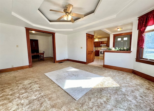 spare room featuring light carpet, ceiling fan, and a raised ceiling